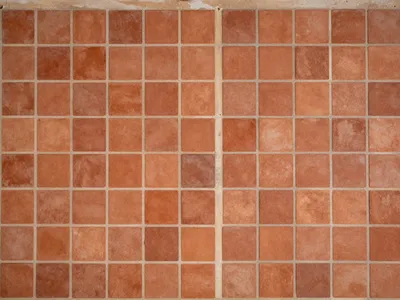 Overhead view of a grid of square terracotta tiles with light mortar joints.