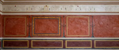 A symmetrical wall fresco in the style of ancient Rome, featuring red panels and decorative elements.