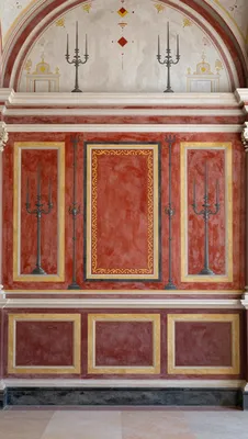 A photorealistic painting of a Roman wall fresco, featuring a symmetrical design with red, gold, and black elements.