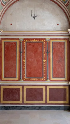 A symmetrical wall fresco in the Pompeian Third Style, featuring red panels, gold accents, and a white upper register.