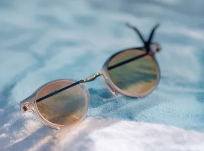 Close-up of designer sunglasses on a blue towel, with a soft focus and shallow depth of field.