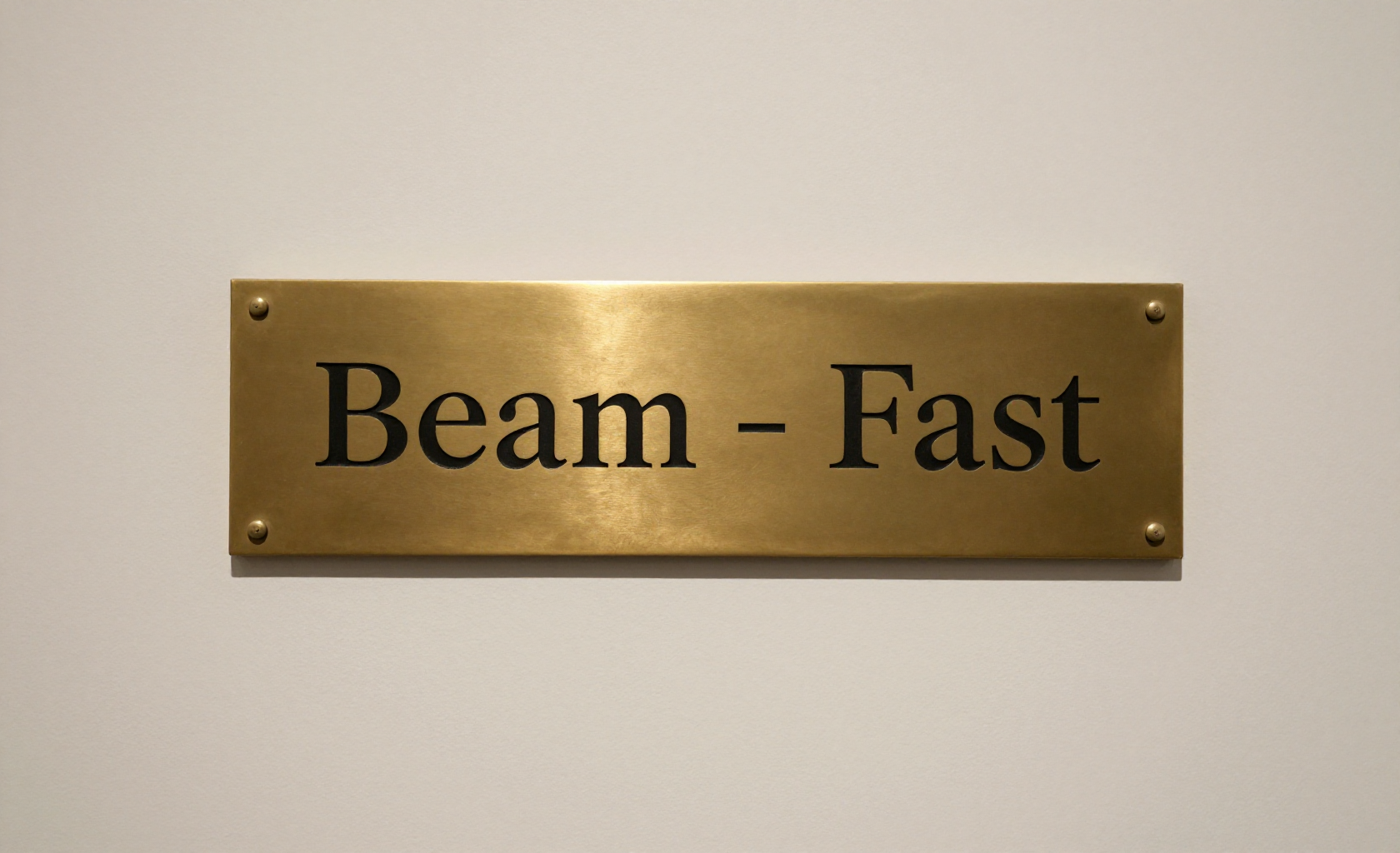 A rectangular brass plaque with the words "Beam - Fast" engraved in black serif font, mounted on a light off-white wall.