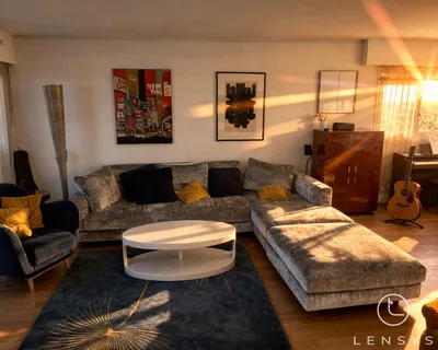 A living room with a gray sofa, a coffee table, and a rug, illuminated by warm sunlight.