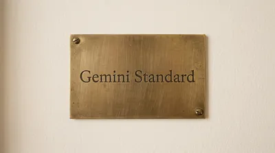 A rectangular brass plaque with "Gemini Standard" engraved in serif font, mounted on a textured off-white wall with two screws.